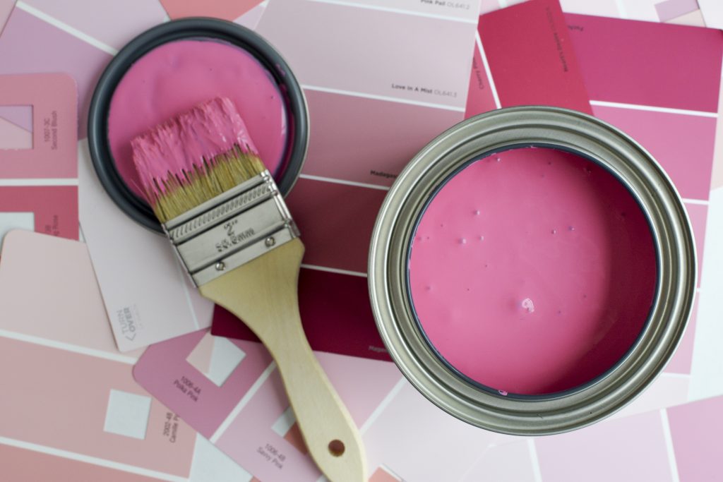 Un pot de peinture rose avec un pinceau