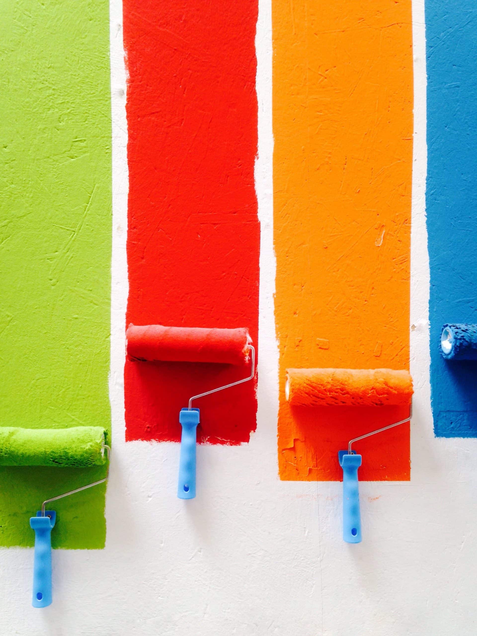 Des rouleaux avec peinture colorées sur un mur blanc